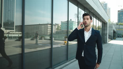 closeup man arguing by phone. businessman walking in slow motion at street