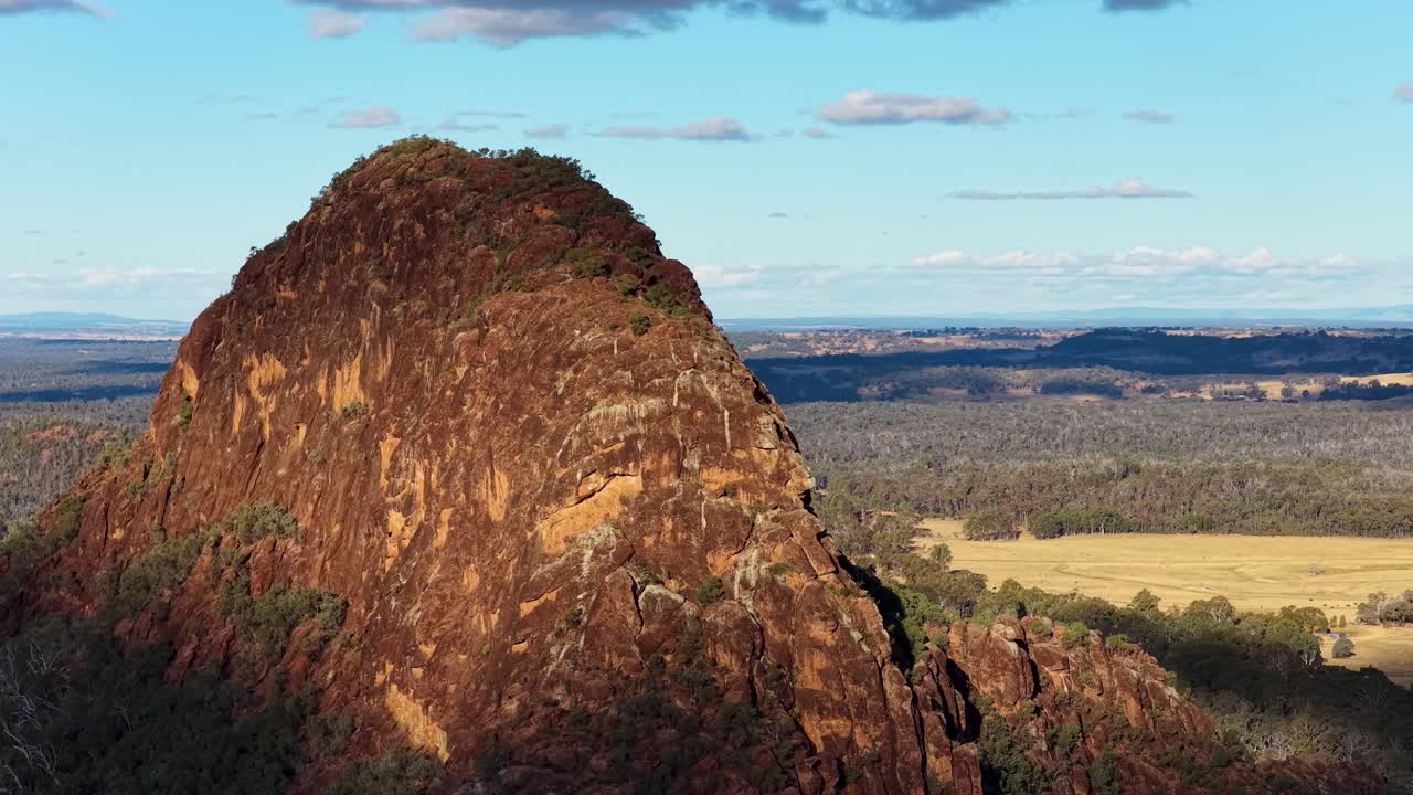 Drone pans around Timor Rock, revealing rugged volcanic outcrop and vast Australian landscape in daylight