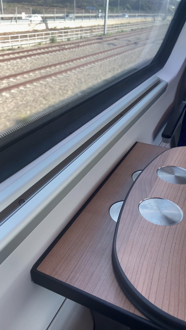 POV train ride commuting to work or travel sightseeing tourism. Table between seats and chairs. Train tracks passing by glass window. Looking out during ride in public transport railway vlog