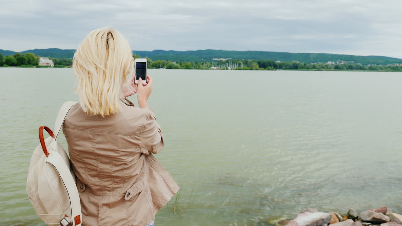 женщина снимает панораму озера
