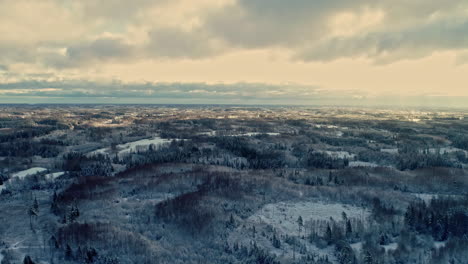 Toma-Aérea-De-Drones-Del-Paisaje-Invernal-Con-Bosque-Cubierto-De-Nieve-En-Tierras-Altas-Frías-A-Lo-Largo-Del-Campo-Rural-En-Un-Día-Nublado