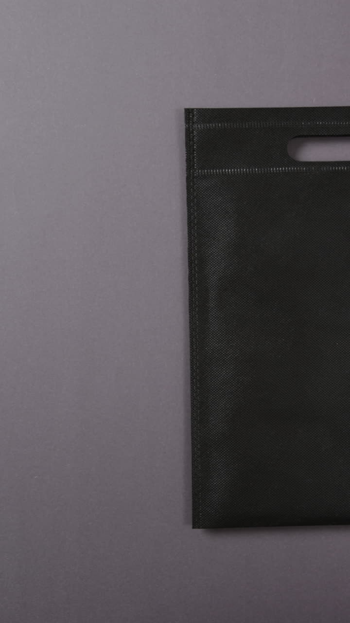Vertical video of black bag and copy space on grey background