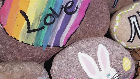 pan from a painted rock with easter bunny to rainbow color heart framing the word love