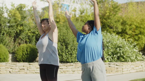 Side-view-of-body-positive-women-warming-up-in-sports-stadium