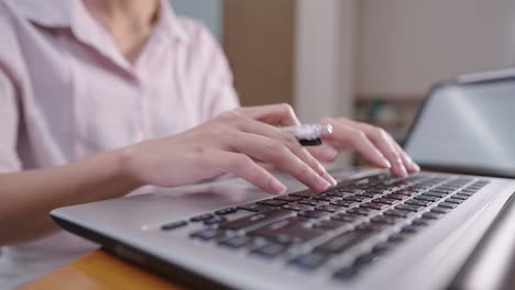 close up mujer contable trabajadora trabajando con computadora portátil escribiendo en el teclado mientras la mano sostiene la pluma, gestión financiera mujer adicta al trabajo, mujer multi-tarea, trabajo de plazo horas extras sola