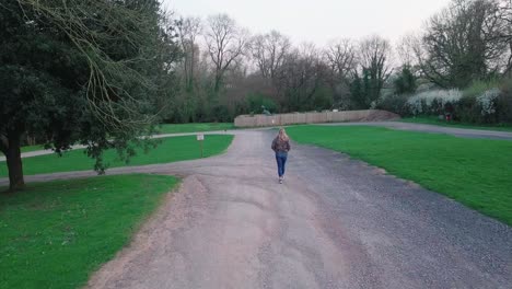 Back-View-Of-A-Woman-Walking-On-The-Pathway-In-The-Village-Of-Wookey-Hole,-Somerset,-England---long-shot