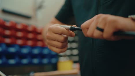 las manos del constructor de clubes de golf giran la cabeza de hierro sobre el eje del club de golf y lo aseguran para la construcción personalizada en el taller en cámara lenta