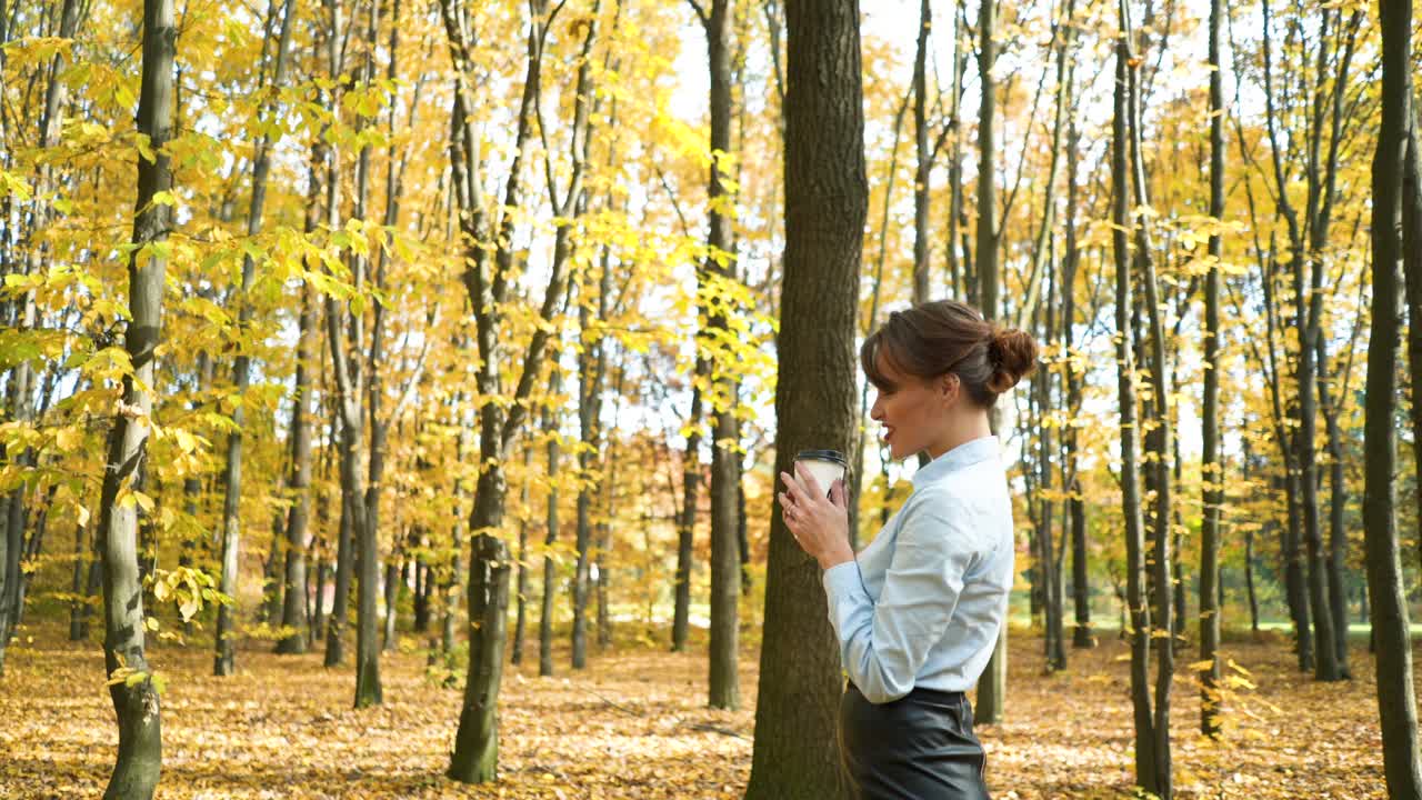 Woman with cup of coffee. Young stylish woman trying to warm up with cup of coffee in autumn park
