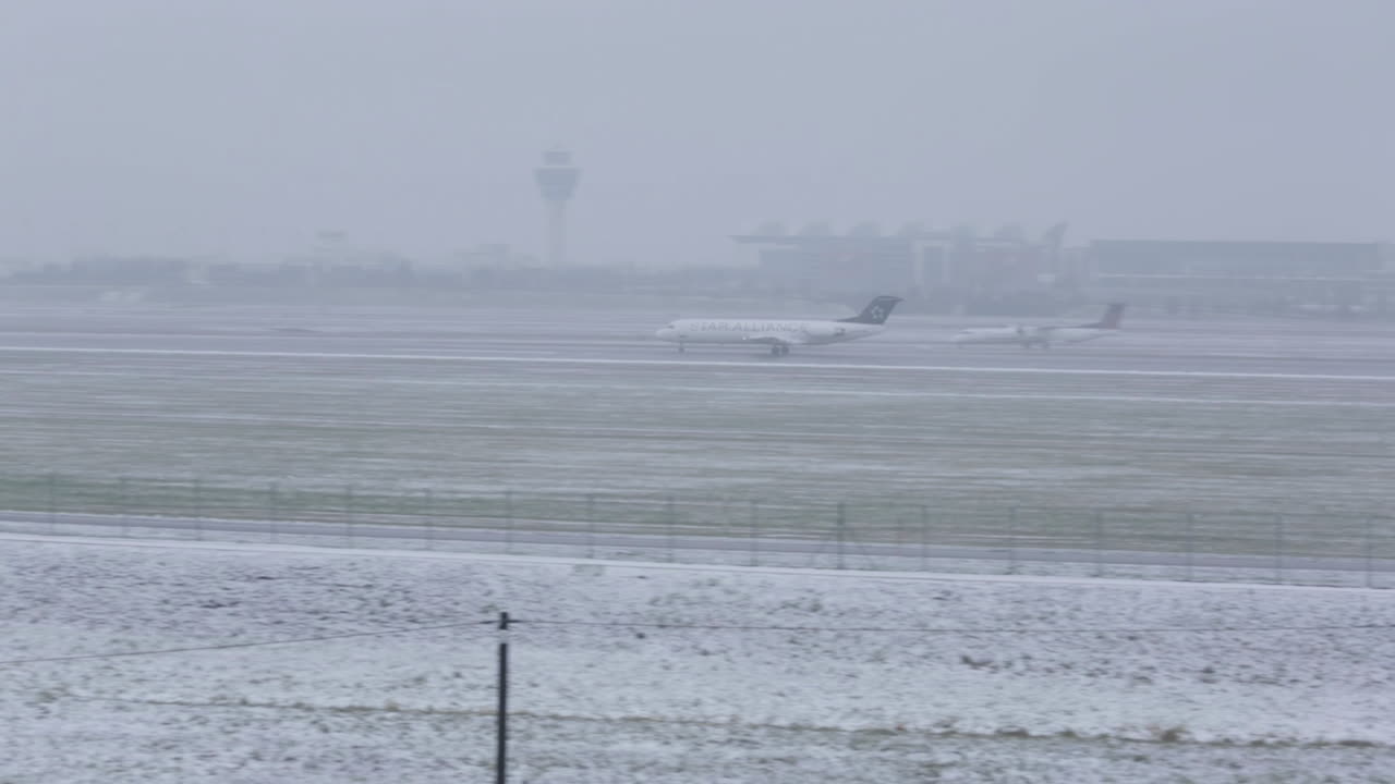 Super wide shot of a plane landing at Munich Airport on a very foggy day in the Winter. Tower of the Airport in the background