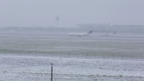 super wide shot of a plane landing at munich airport on a very foggy day in the winter. tower of the airport in the background