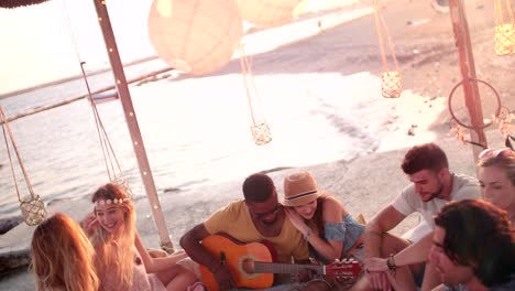 young multi-ethnic hipster friends with guitar at summer beach party