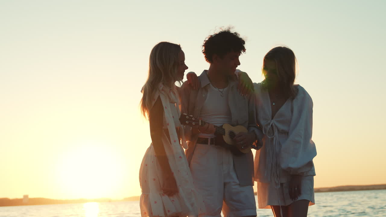 해가 지는 해변에서 우쿨레를 연주하는 친구들