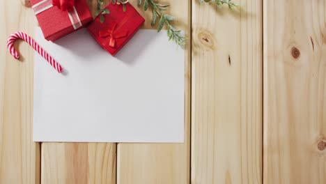 Video-of-christmas-decorations-with-white-card-and-copy-space-on-wooden-background