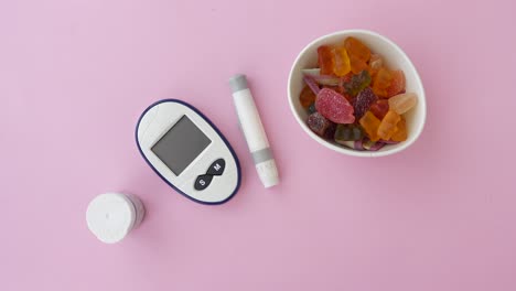 diabetes testing kit and colorful candy on a pink background