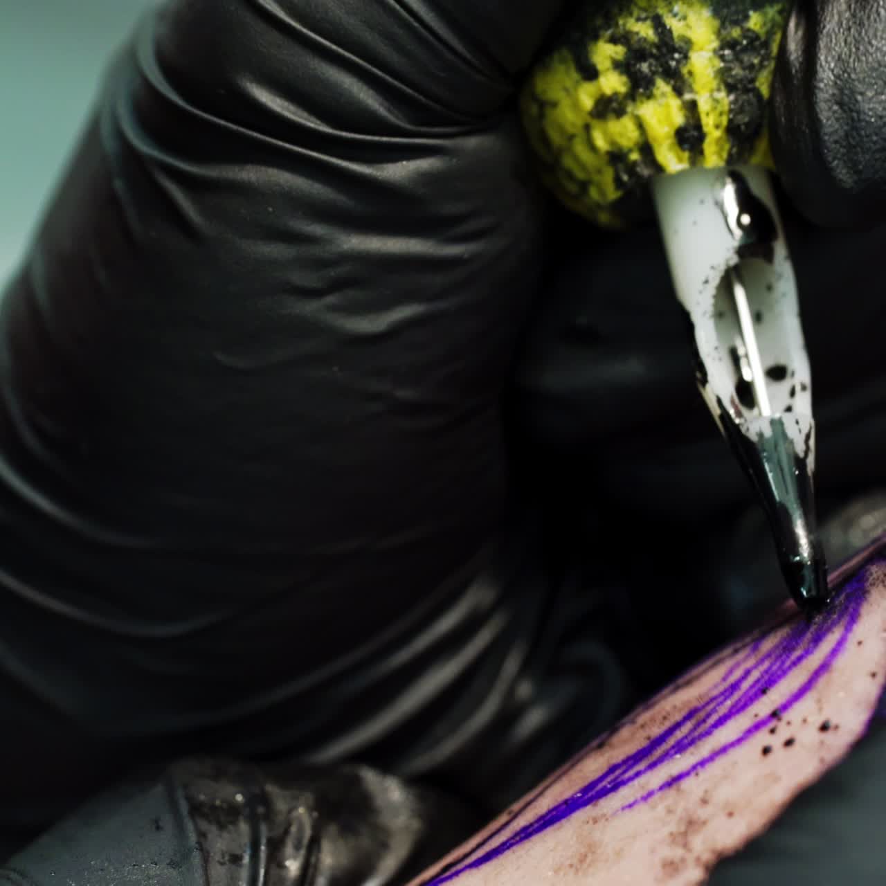 Tattoo artist carefully draws a line with special ink machine. Having a tattoo in a modern tattoo parlour. Close up