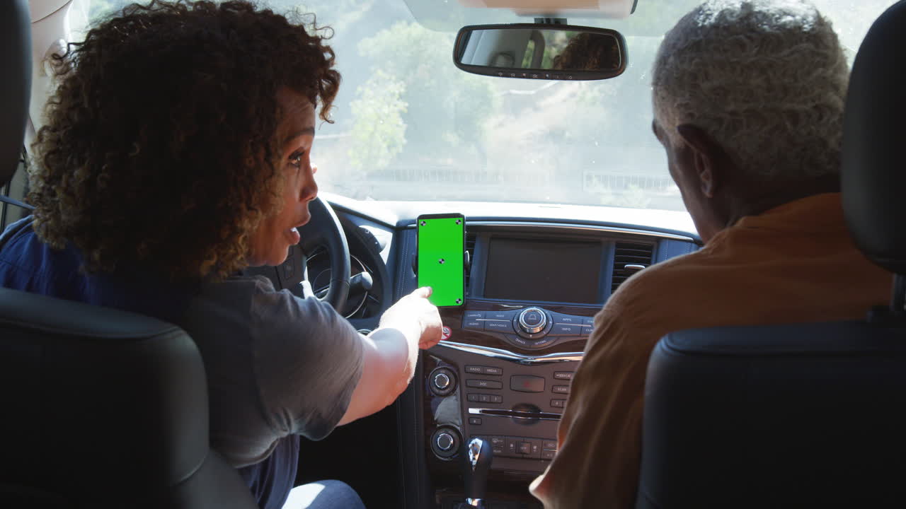 una pareja de ancianos afroamericanos en un viaje por el campo usando navegación por satélite en un teléfono móvil