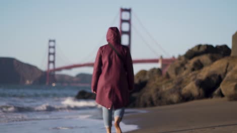 young girl with purple jacket walking on the baker beach in san francisco california, close up, focus shift