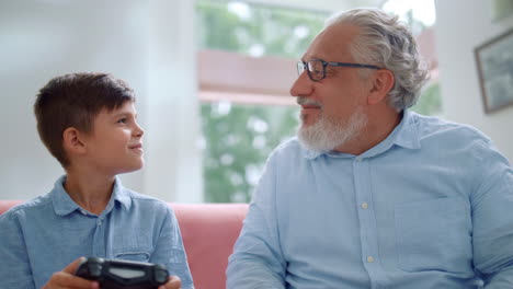 Focused-senior-man-and-boy-playing-video-game-with-joysticks-at-home