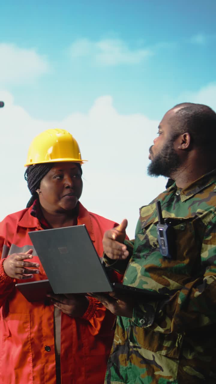 Vertical video Military personnel on offshore rig monitoring defense systems with laptop