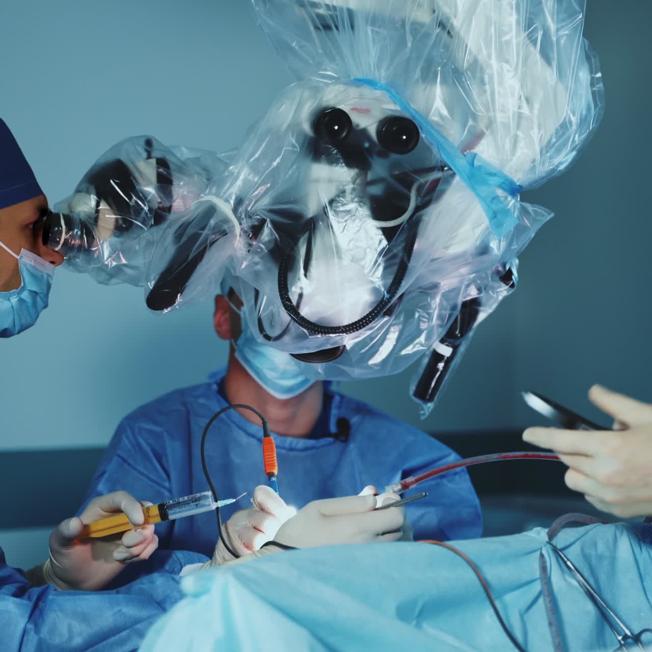 Surgery professionals look into microscope hanging from the ceiling above the patient. Team of doctors perform neurosurgical operation
