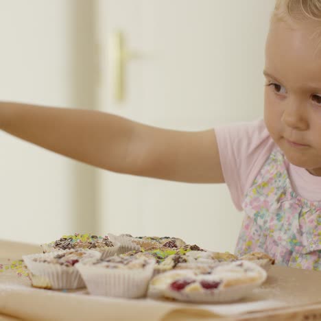 Close-up-on-girl-sprinkling-toppings-on-muffins