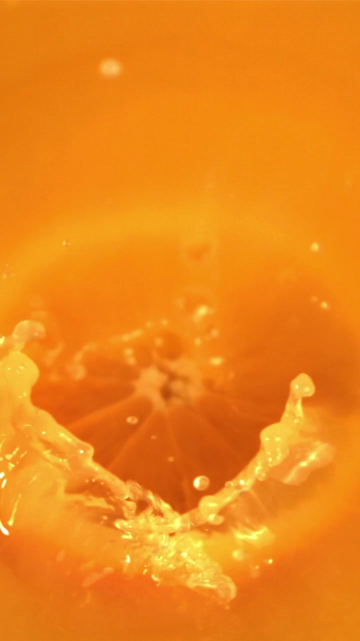 Fetta d'arancia rinfrescante che cade in succo d'arancia vibrante