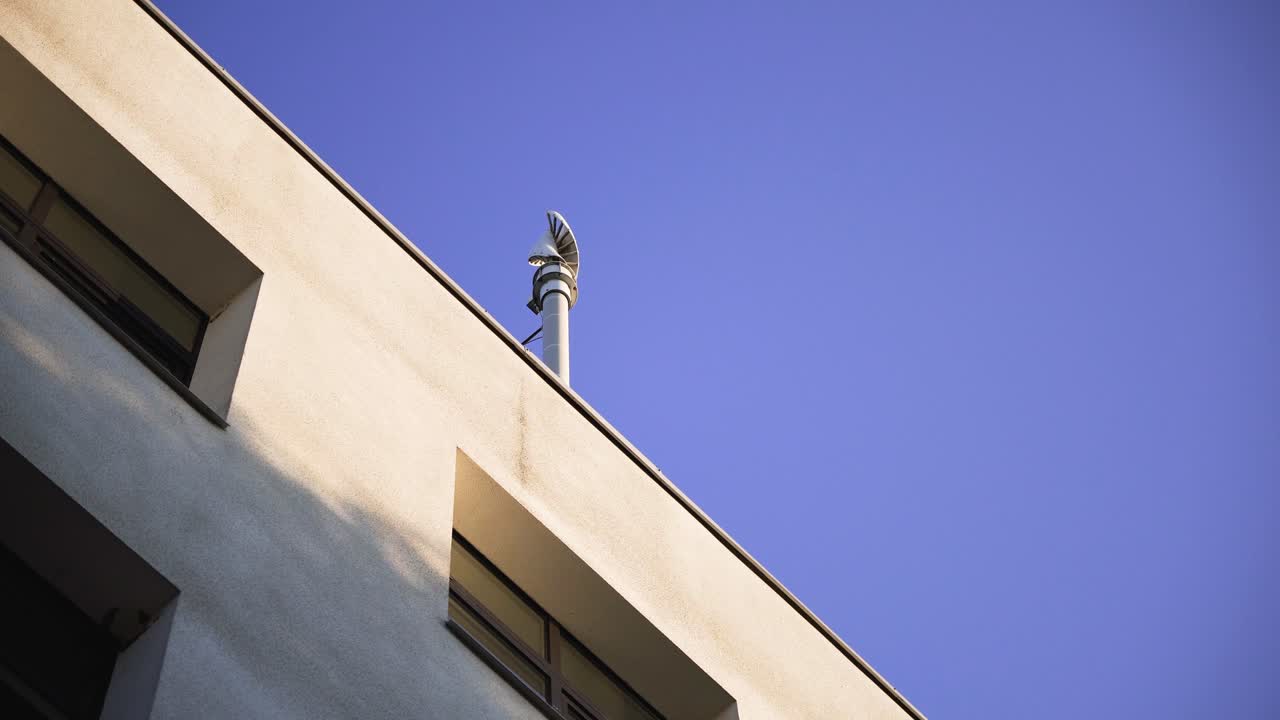 Low-angle view of a spinning small wind turbine on a building's roof
