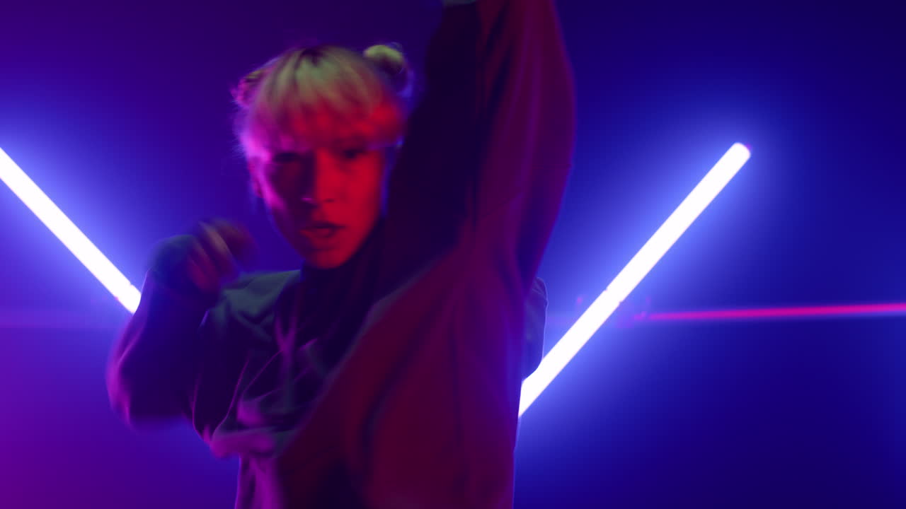 프로 퍼포머가 스튜디오 라이락 백라이트에서 솔로로 활기차게 춤을 추고 있습니다.