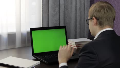 Man-have-video-call-conference-on-laptop-with-green-screen.-Distance-work-online