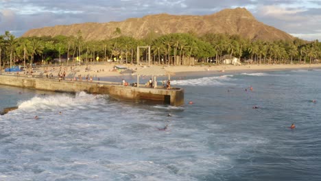 Sunset-in-Waikiki-Hawaii,-sweeping-view-of-the-surf,-city,-and-beyond