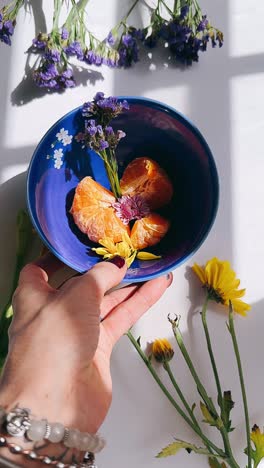 mano sosteniendo un cuenco de naranjas y flores