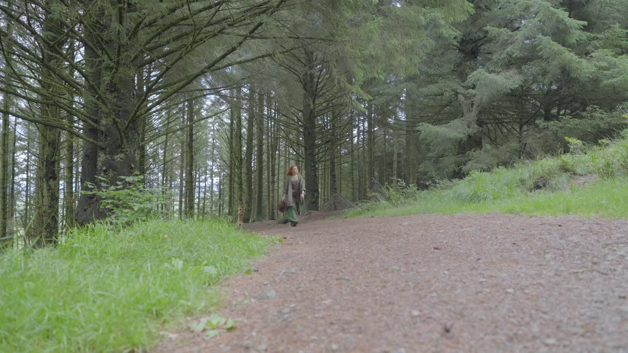 여자 는 여름 날 에 카메라 를 향해 그늘진 숲 길 을 따라 절반 의 속도 로 느리게  ⁇ 고 있다