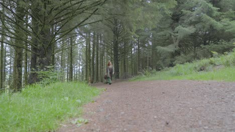 girl walking along shady forest path towards camera on summer day at half speed slow motion