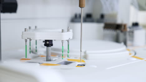 long metal needle moving from one slot to another. advanced equipment working in the science laboratory for blood test.