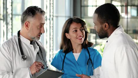 multi-ethnic male and female doctors talking and smiling in clinic