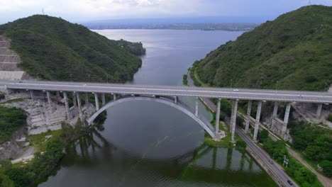 Aerial view of bridge over lake with cars moving on road surrounded by mountains. Córdoba, Argentina