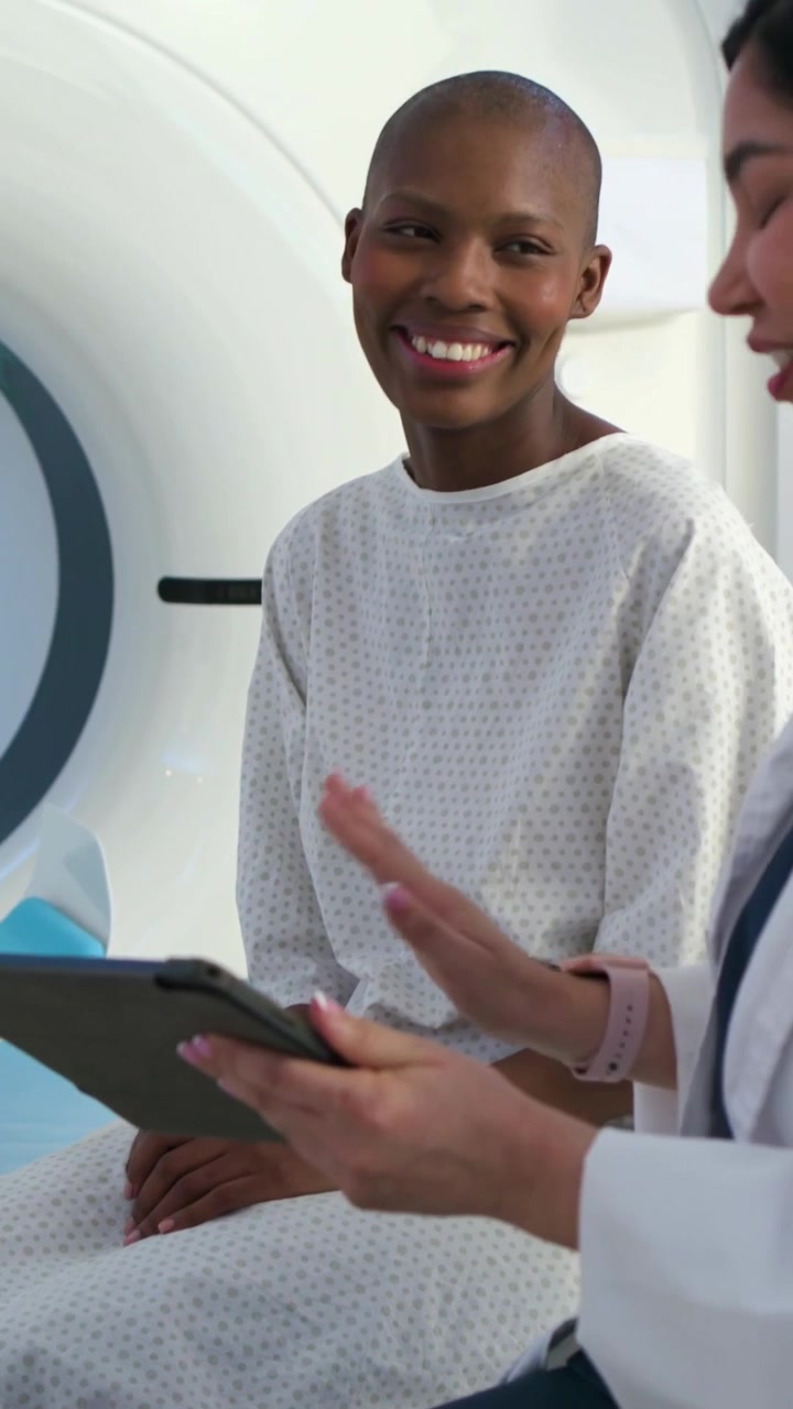 Vertical video: Tapping tablet, clinician presenting info in clinic, patient in gown nodding