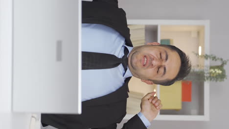 vertical video of home office worker man yawns and relaxes at the camera.