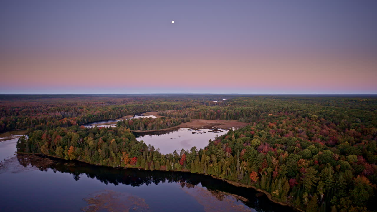 Drone look at a river cradled by widespread autumn woods