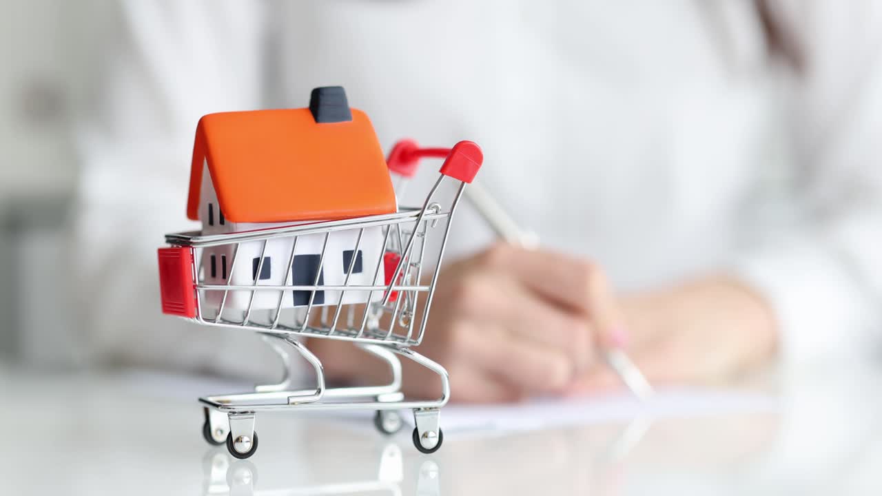 Primer plano de un agente rellenando un contrato de venta de una casa.