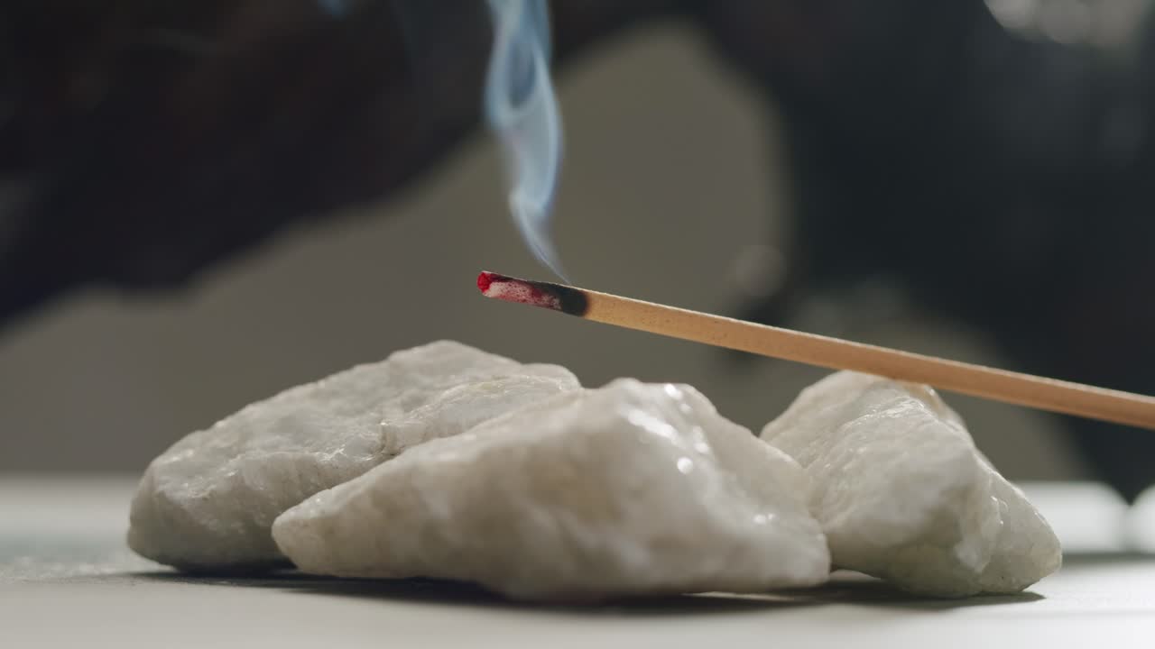 Person holding Palo Santo wood stick in hand, aromatic Palo Santo burning on black background, smoke spreading around, slow motion video clip, high quality 4k close up footage. High quality 4k footage