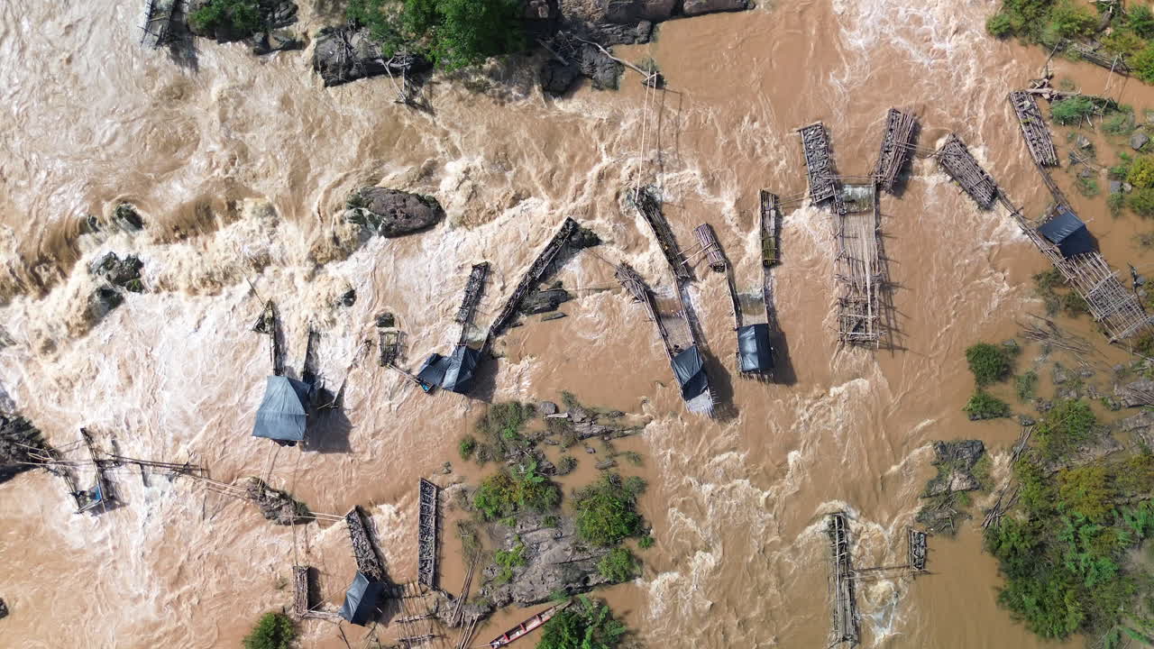 Perangkap ikan tradisional di sepanjang Sungai Mekong dekat 4000 pulau Laos, rekaman udara drone dari atas air yang mengalir.