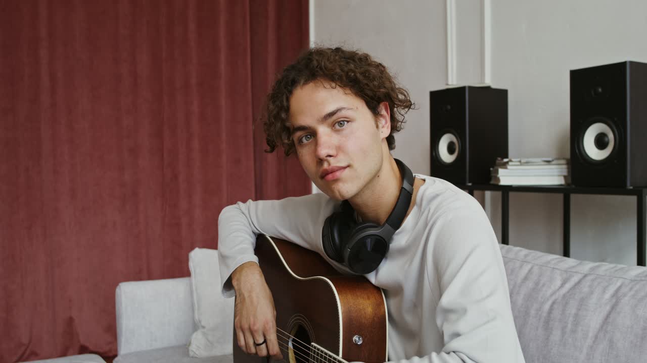 Jovem tocando guitarra acústica em casa