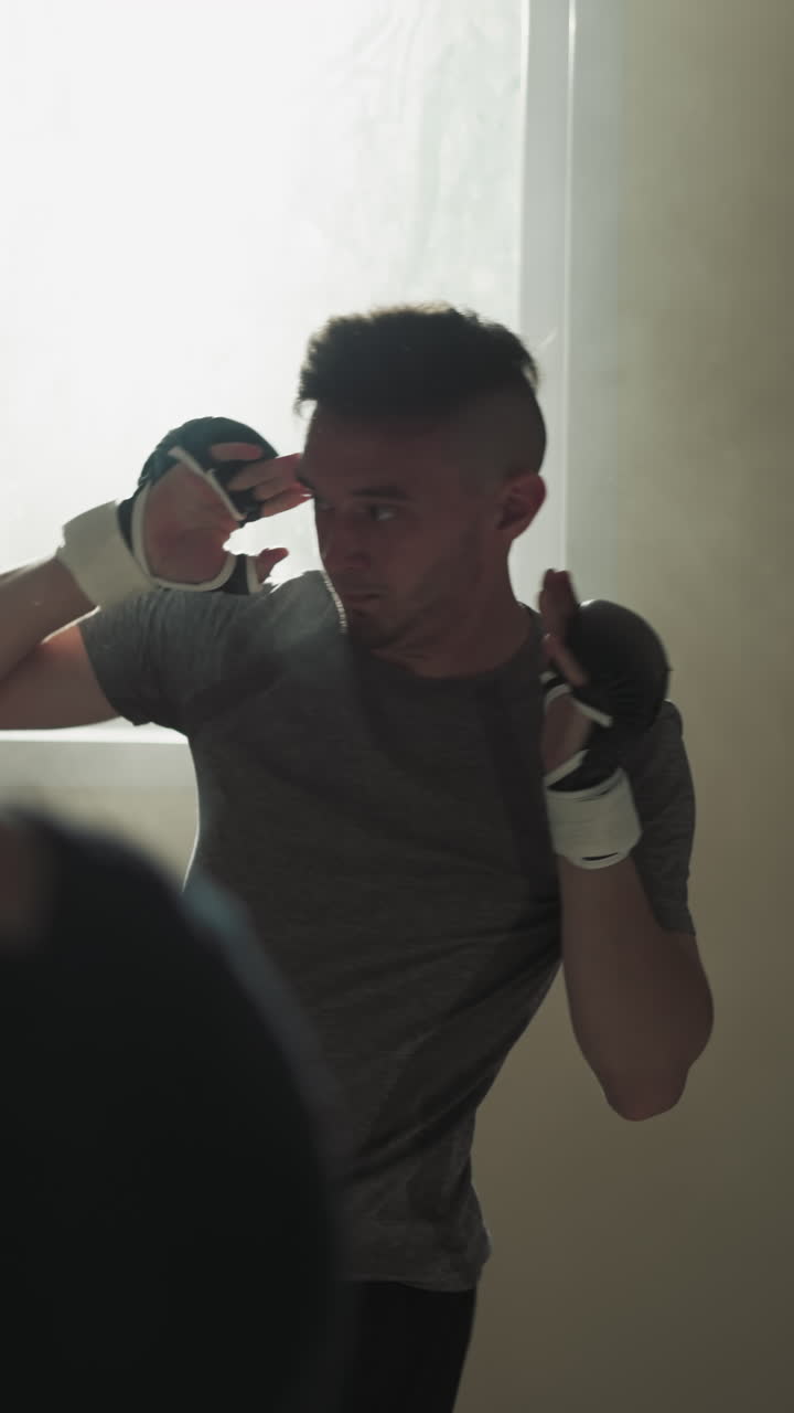 Kick-boxers beat punching bags together in sports club. Professional sportsmen kick and punch hanging equipment in fighting team gym slow motion