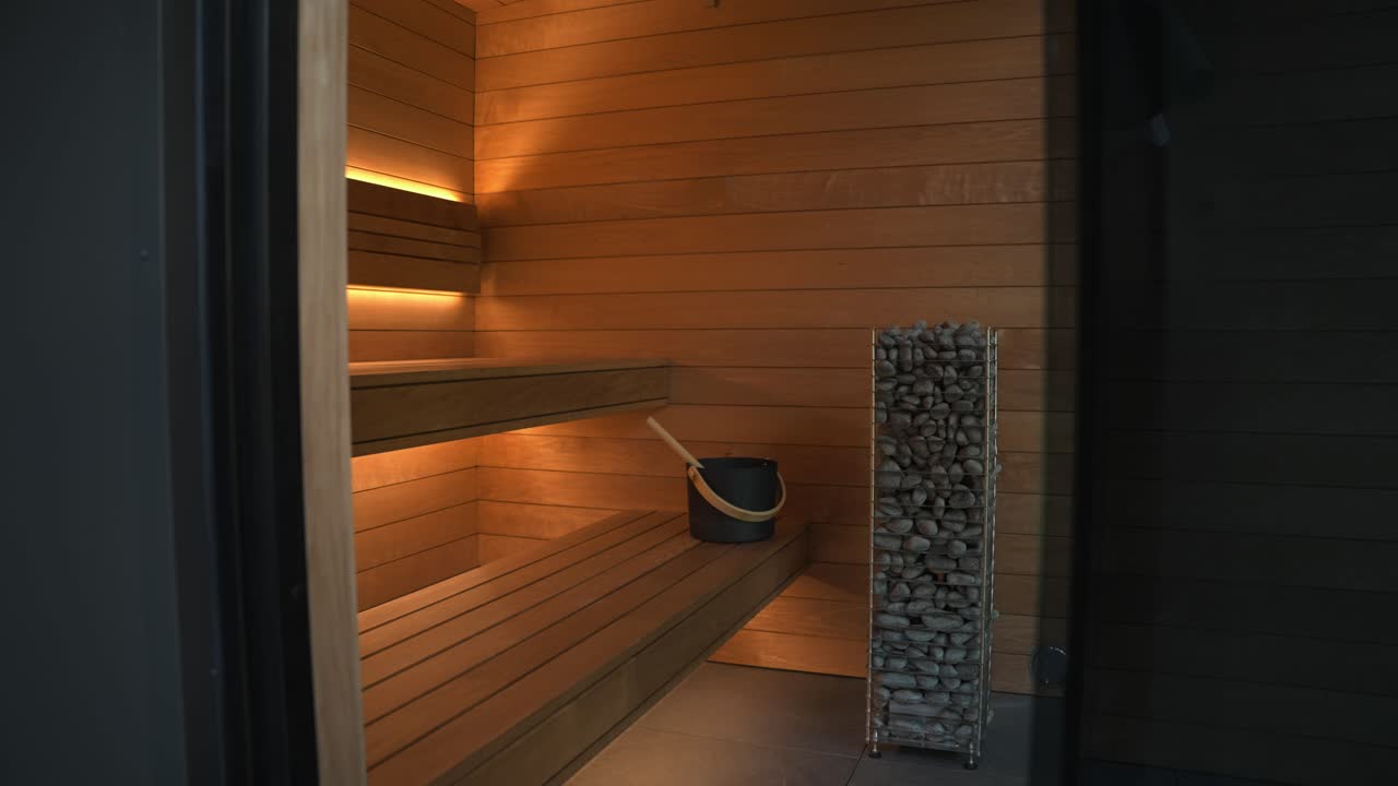 empujar lentamente dentro de una luxuosa sauna de madera de cedro completa con calor de roca alta, bancos de dos niveles y ventana de piso a techo que muestra la vista hacia el área boscosa