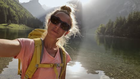 young woman taking a selfie on a hike by a mountain lake