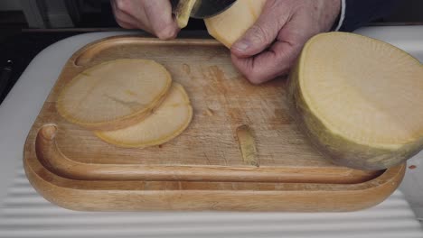 pelar rebanadas de sueco antes de cortarlo para hacer una sopa de verduras de raíz hecha a mano