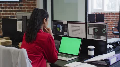 Woman-using-laptop-while-sitting-on-her-desk-at-office