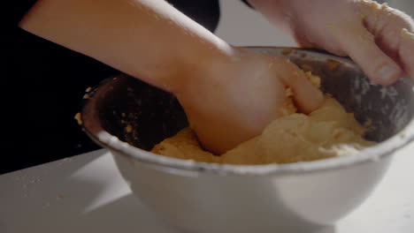 mujer joven formando masa en un bol para un pastel en la cocina de casa
