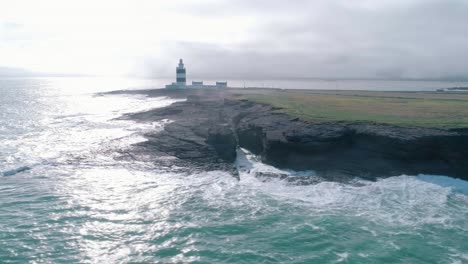 golven raken een rotsachtige kust door een vuurtorenantenne